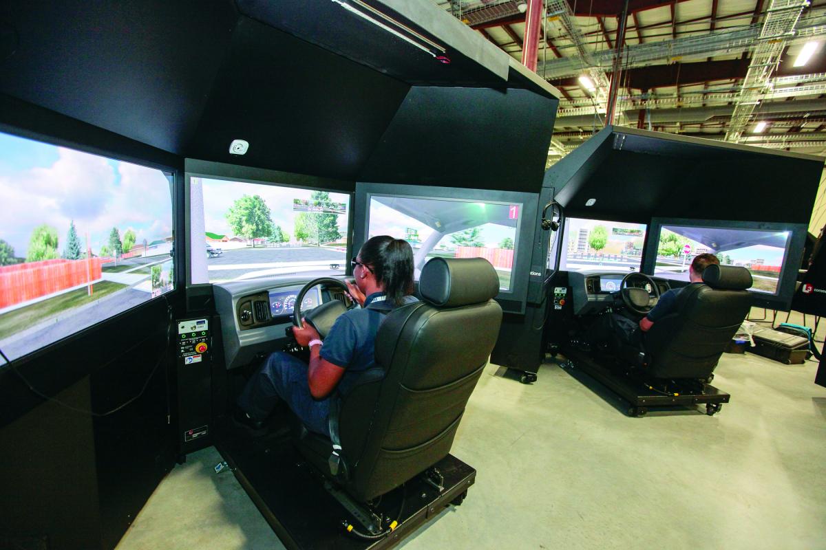 A female student uses a driving simulator to experience training scenarios that would be unsafe (such as avoiding pedestrians running into intersection) on a standard driving track.