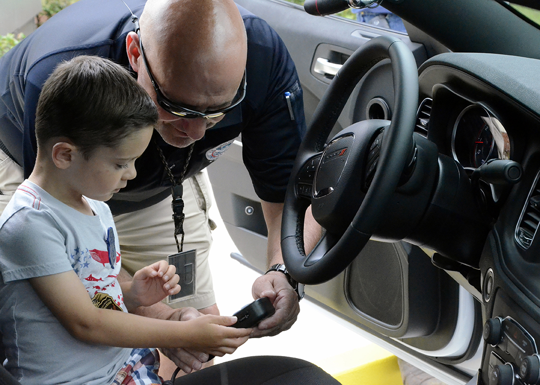 Youth experiences firsthand how to operate the 2019 Dodge Charger Police Package siren system at the Federal Law Enforcement Training Centers, National Police Week Law Enforcement Community Day in Glynco, Georgia, on May 15, 2019. (Photo by Brandon Spragins, FLETC PCO)