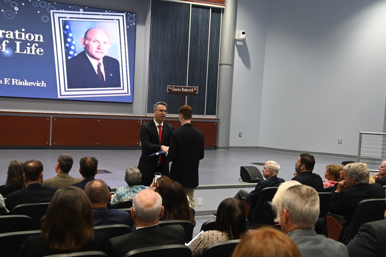 Acting Director Paul E. Baker presents U.S. flag which flew over FLETC-Artesia and FLETC-Glynco to Former Director Charles F. Rinkevich’s grandson, David Pathi during the Celebration of Life Ceremony for Former Director Charles F. Rinkevich. (Photo by Diamond Sanders/OPA)