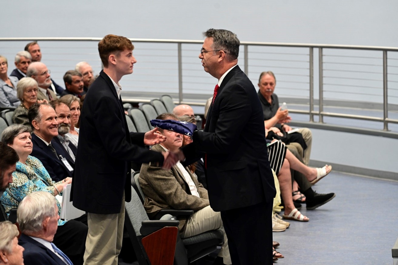 Acting Director Paul E. Baker presents U.S. flag which flew over FLETC-Artesia and FLETC-Glynco to Former Director Charles F. Rinkevich’s grandson, David Pathi during the Celebration of Life Ceremony for Former Director Charles F. Rinkevich. (Photo by Diamond Sanders/OPA)
