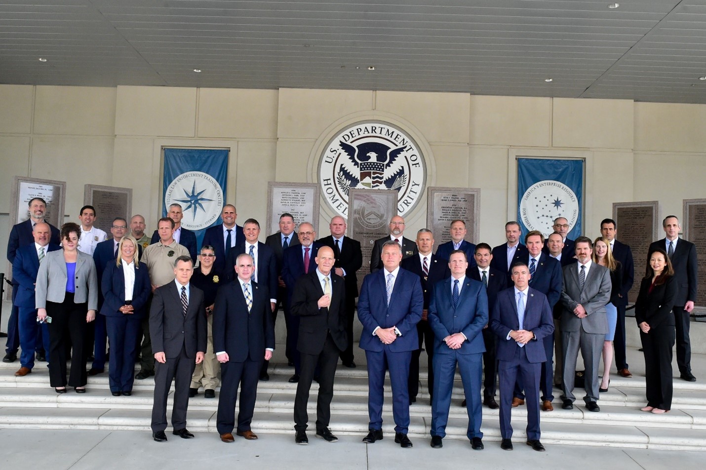 Director Walters, Deputy Director Fallon, and the Partner Organization Training Executives Forum attendees take a group photo in front of the building 912 Graduate Memorial prior to scheduled briefings on critical issues in federal law enforcement training and the contemporary environment of training for partner organizations on April 21, 2022, on Glynco, Georgia.