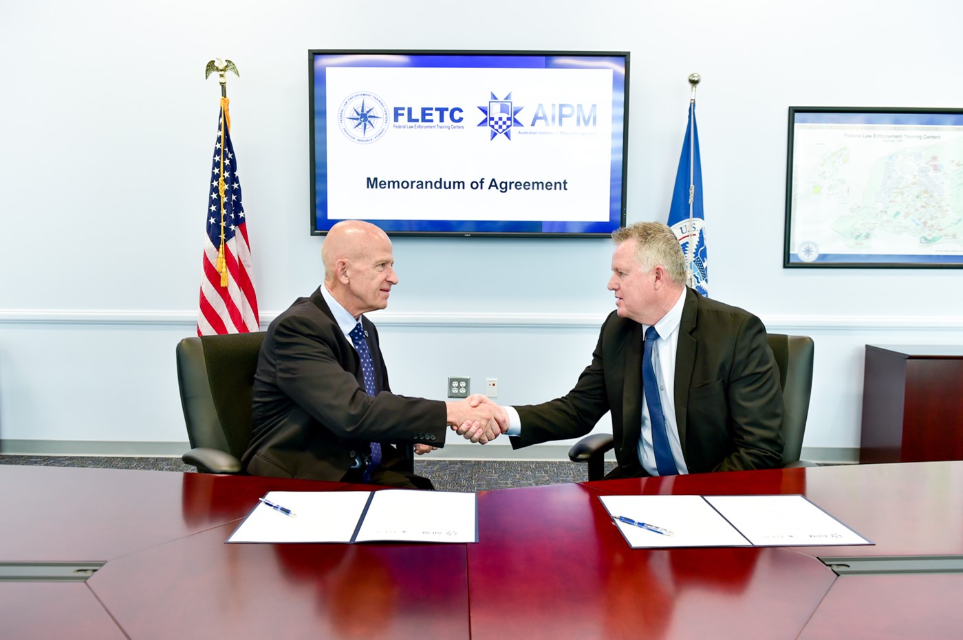 On September 23, 2022, Thomas J. Walters, Director of the Federal Law Enforcement Training Centers (FLETC), and Stuart Bartels, Executive Director of Australian Institute of Police Management (AIPM), shake hands after signing a Memorandum of Agreement to collaborate as training partners in professional exchanges. (Photo by David Tucker/FLETC)